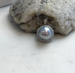 Lustrous Tahitian pearl framed by clear stones and suspended from a delicate silver chain.
