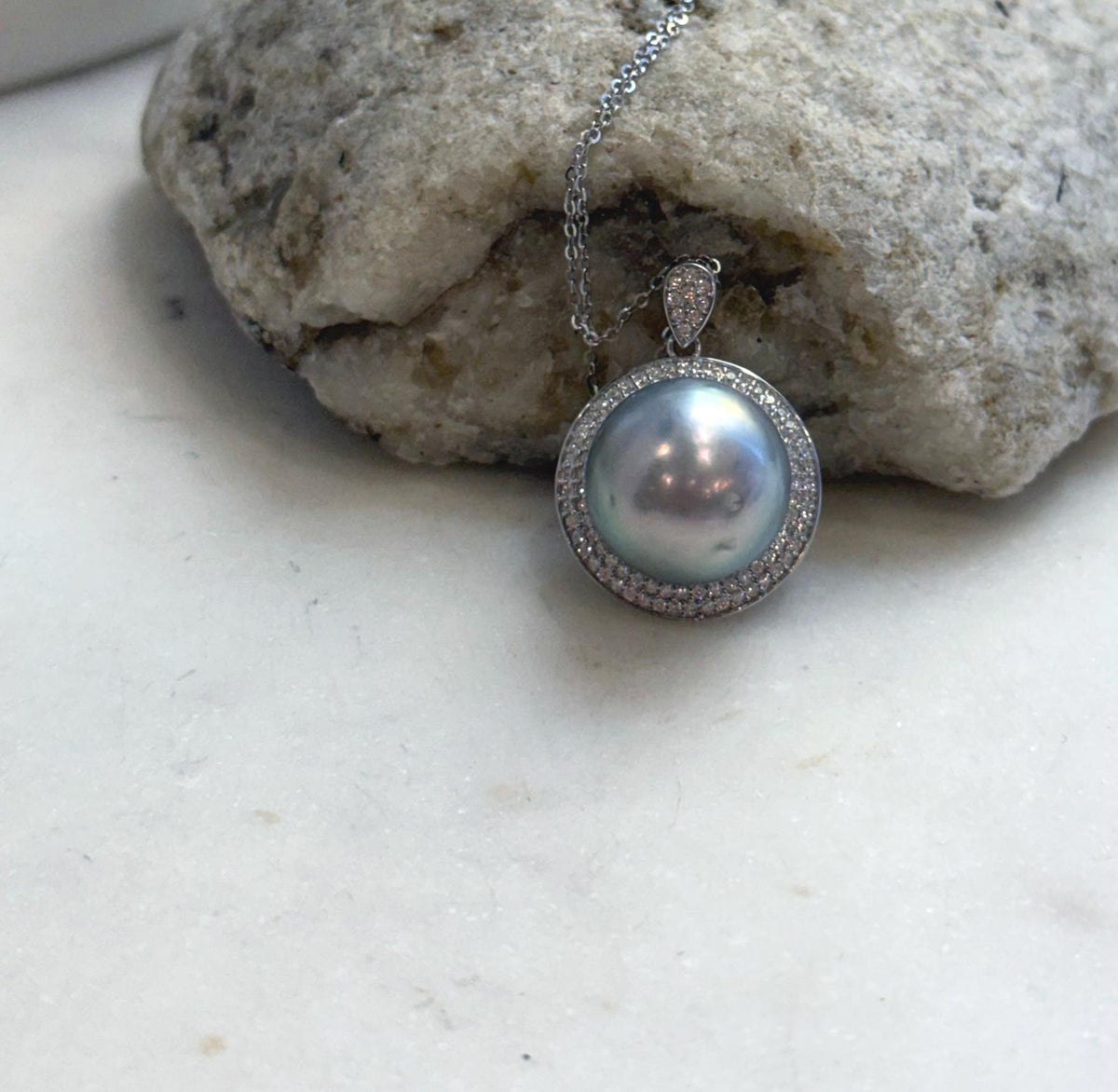 Tahitian saltwater pearl necklace featuring a circular crystal halo and a teardrop-shaped bail.