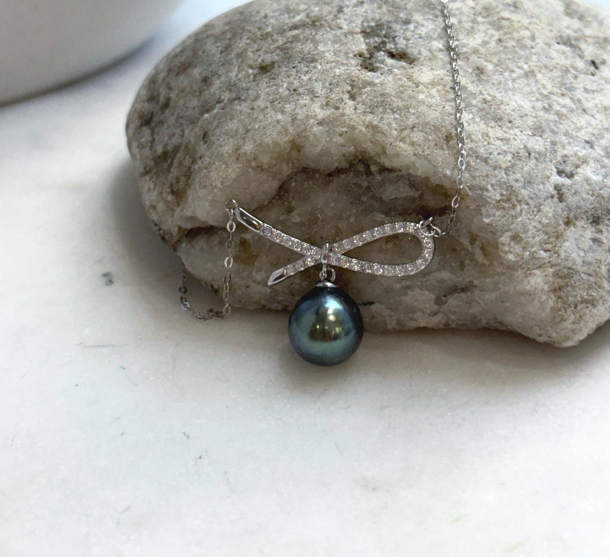Tahitian pearl necklace featuring an open ribbon loop and crossing silver bow tails.