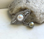 Pearl pendant brooch featuring a round white pearl and dangling dark pearl