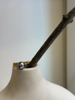 Tahitian pearl ring displayed on a white marble surface beside a stone