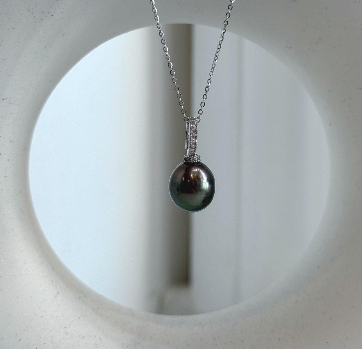 Peacock green pearl pendant featuring a reflective surface and sparkling crystal accents.