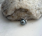 Tahitian pearl necklace displayed against a cream circular cutout stand, showing its silver orbit ring.