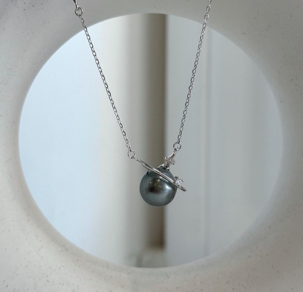 Lustrous green-gray Tahitian pearl framed by a polished silver ring with a sparkling accent.