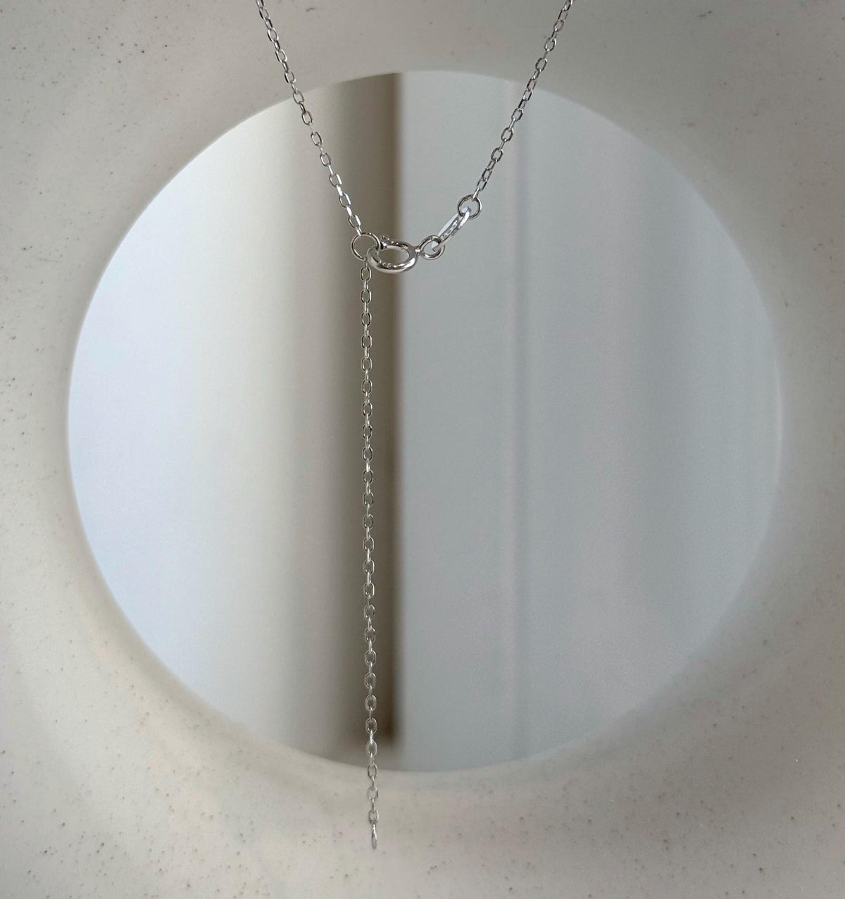 Saturn-inspired Tahitian pearl pendant with a tilted silver orbit and a small star above the pearl.