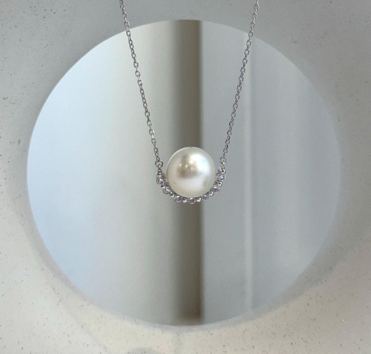 Sparkling crescent pendant paired with a white South Sea pearl in sterling silver.