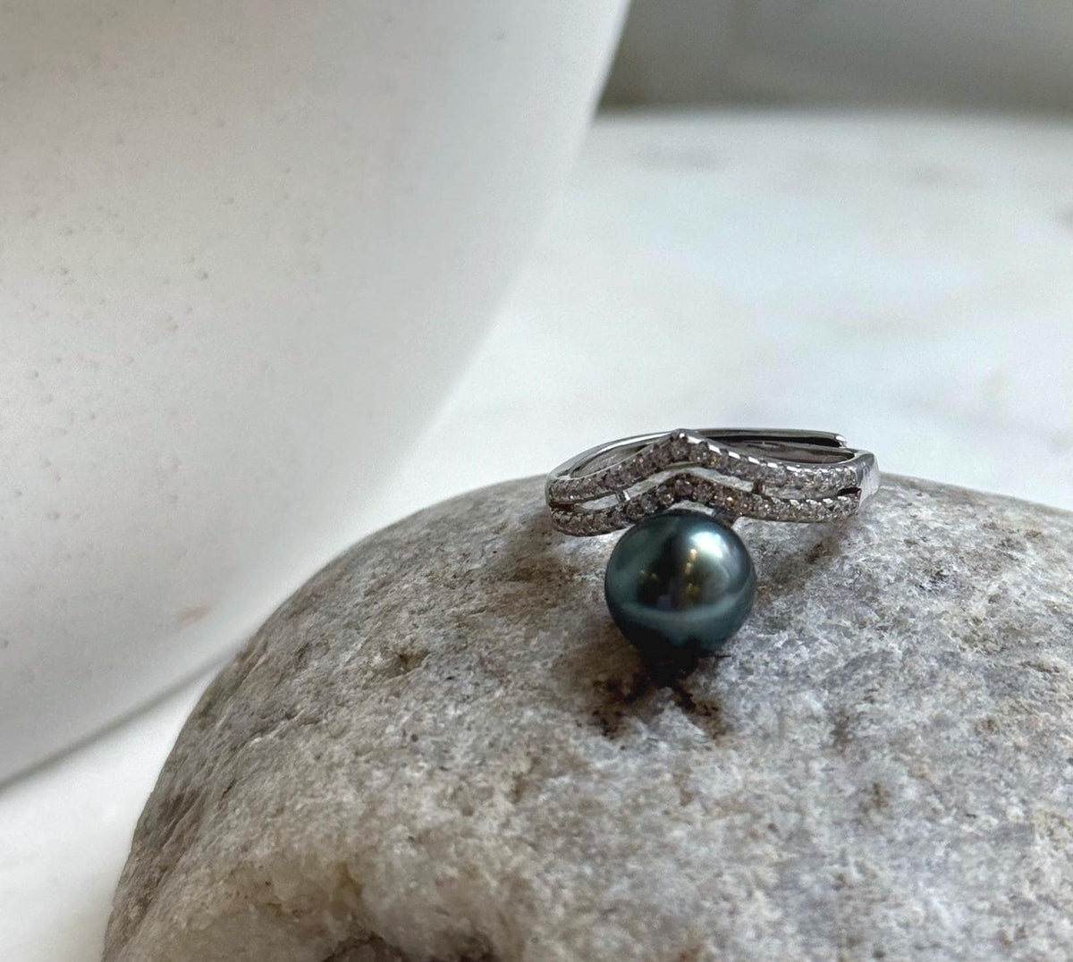Tahitian pearl ring displayed beside a white ceramic vase and natural stone.