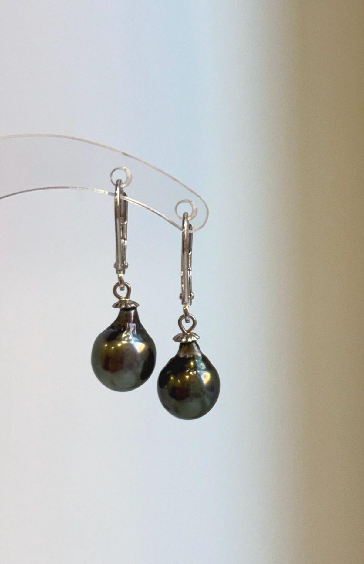Sterling silver leverback earrings showcasing Tahitian pearls with a reflective surface.