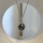 Dark Tahitian keshi pearl set within a curved sterling silver halo with clear stone accents.