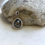 Dark Tahitian keshi pearl set within a curved sterling silver halo with clear stone accents.
