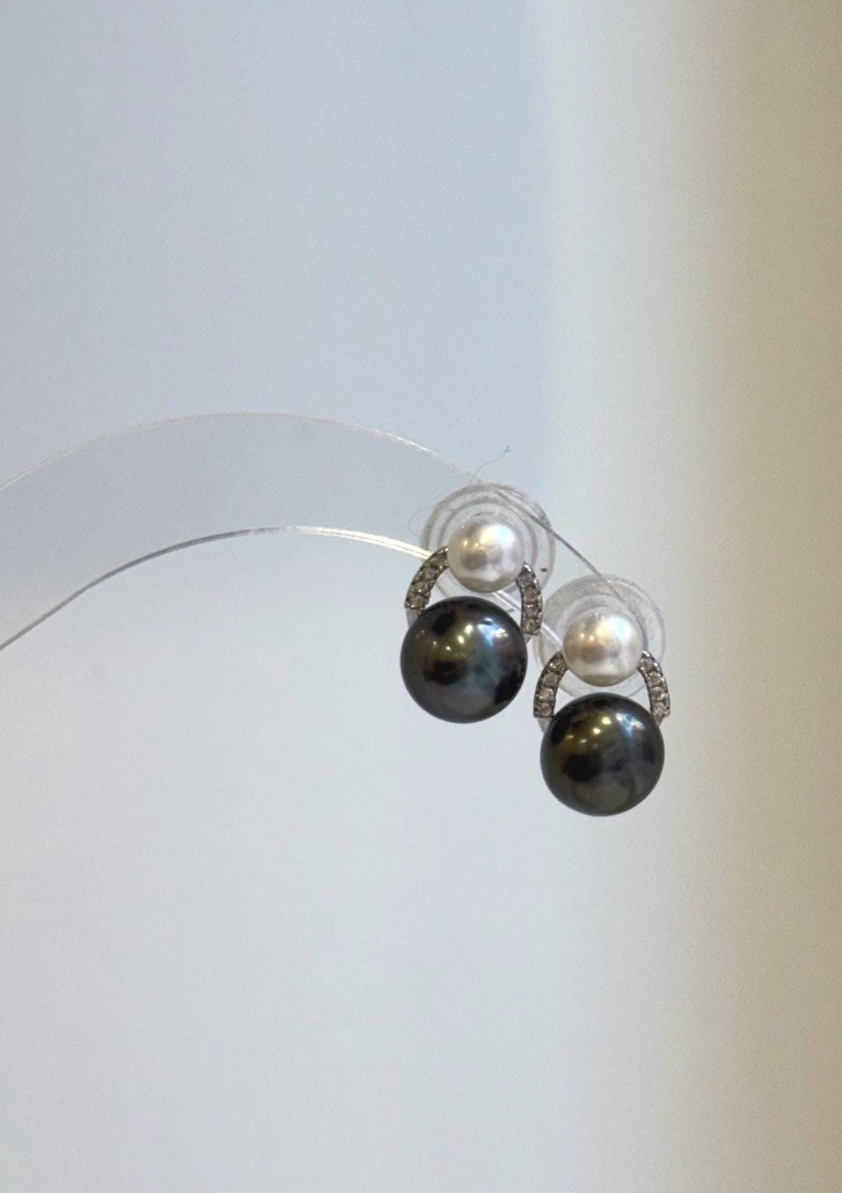 Dark and white pearl earrings with curved, sparkling sterling silver accents.