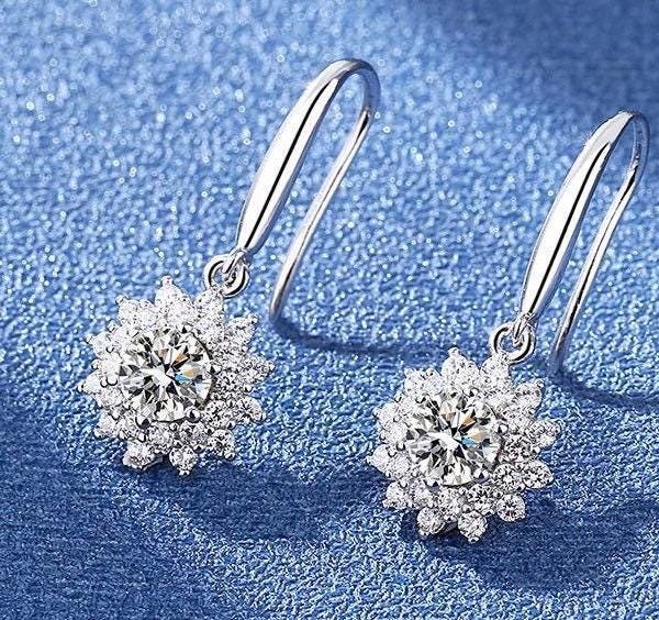 Round moissanite center stones framed by sparkling petal-like accents on silver drop earrings.
