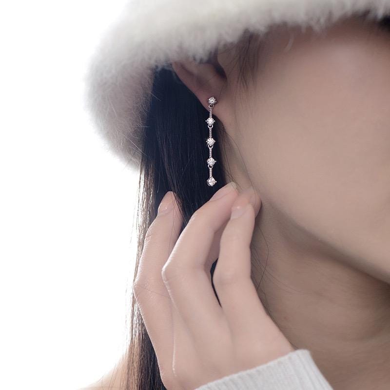 Linear moissanite drop earrings with open spaces between five round stone settings.