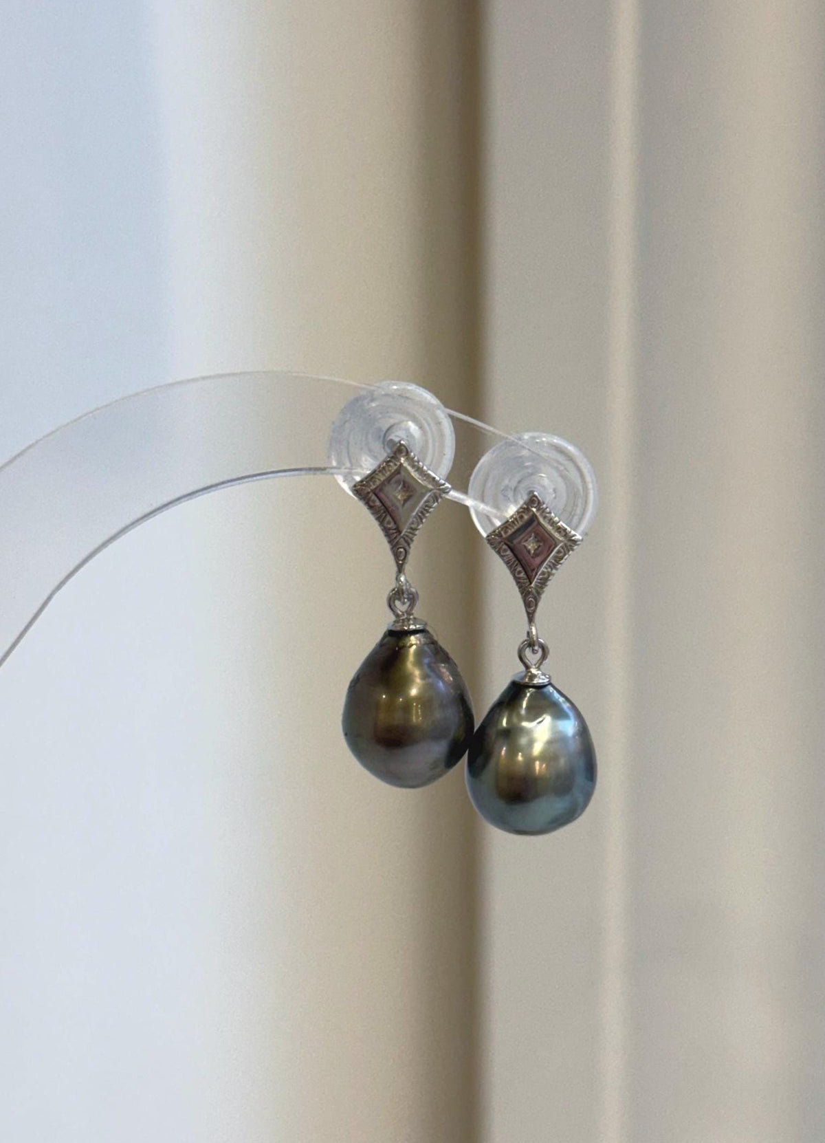 Tahitian pearl dangle earrings with reflective surfaces and geometric silver details.
