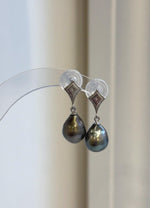 Tahitian pearl dangle earrings with reflective surfaces and geometric silver details.