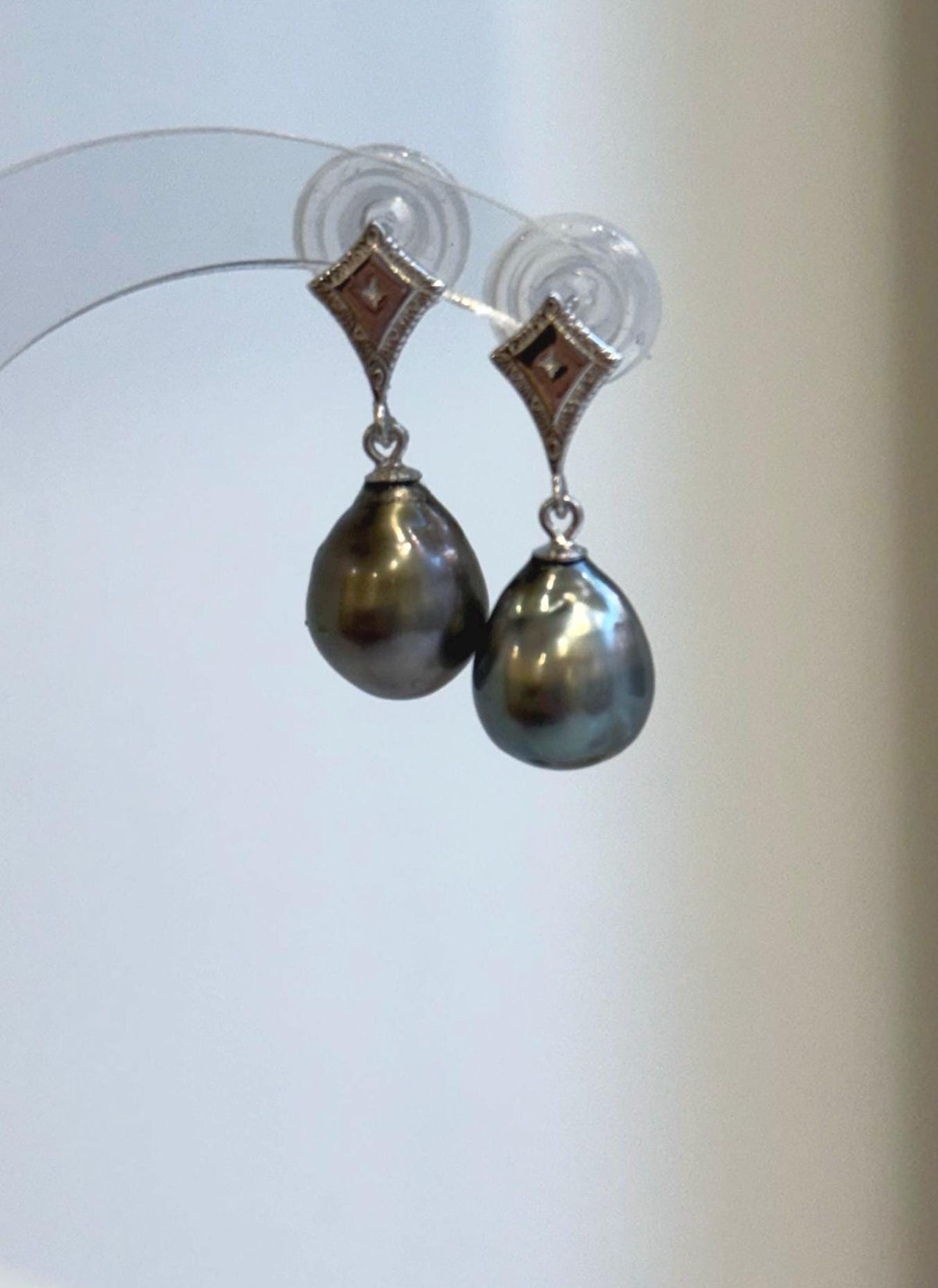 Dark Tahitian pearl earrings with bronze highlights and blue-green reflections.