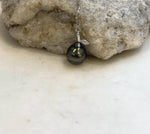 Lustrous hunter green saltwater pearl beneath a curved silver bail and small leaf detail.