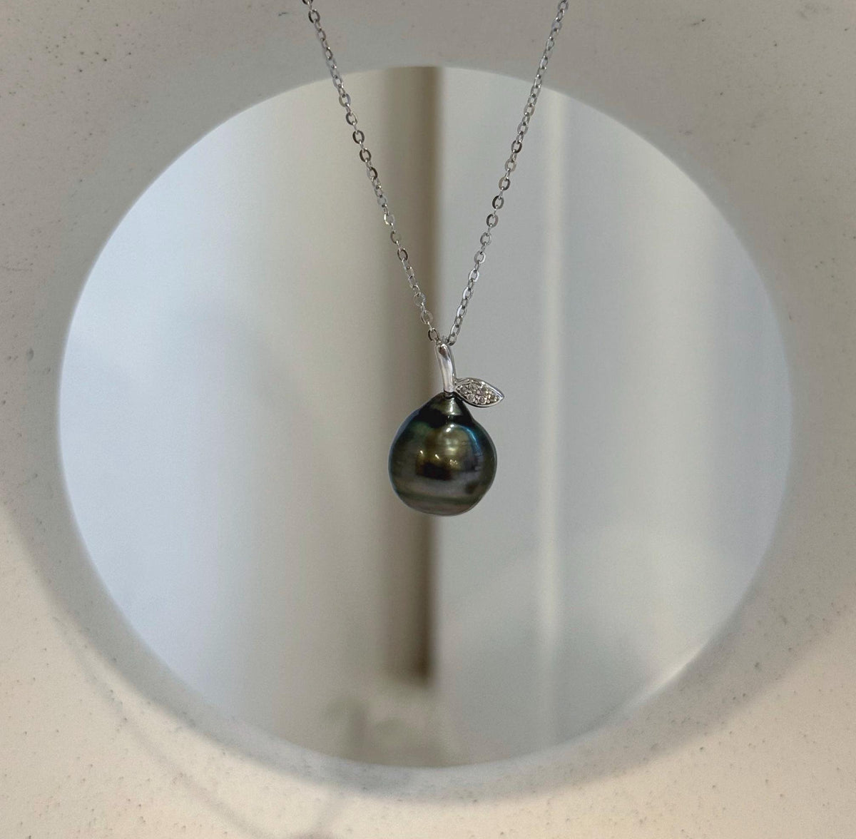 S925 sterling silver necklace with a dark drop-shaped Tahitian pearl and leaf-inspired setting.