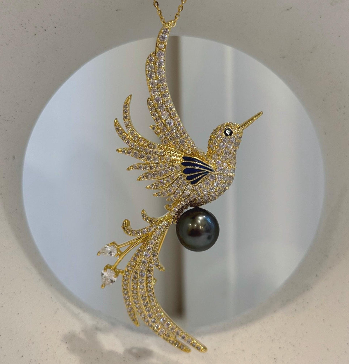 Bird-inspired brooch featuring a reflective Tahitian black pearl.