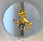 Tahitian pearl rocking horse brooch with clear baguette stones along the curved rocker.