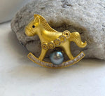 Horse brooch pendant with a black eye and five circular ornaments across its body.