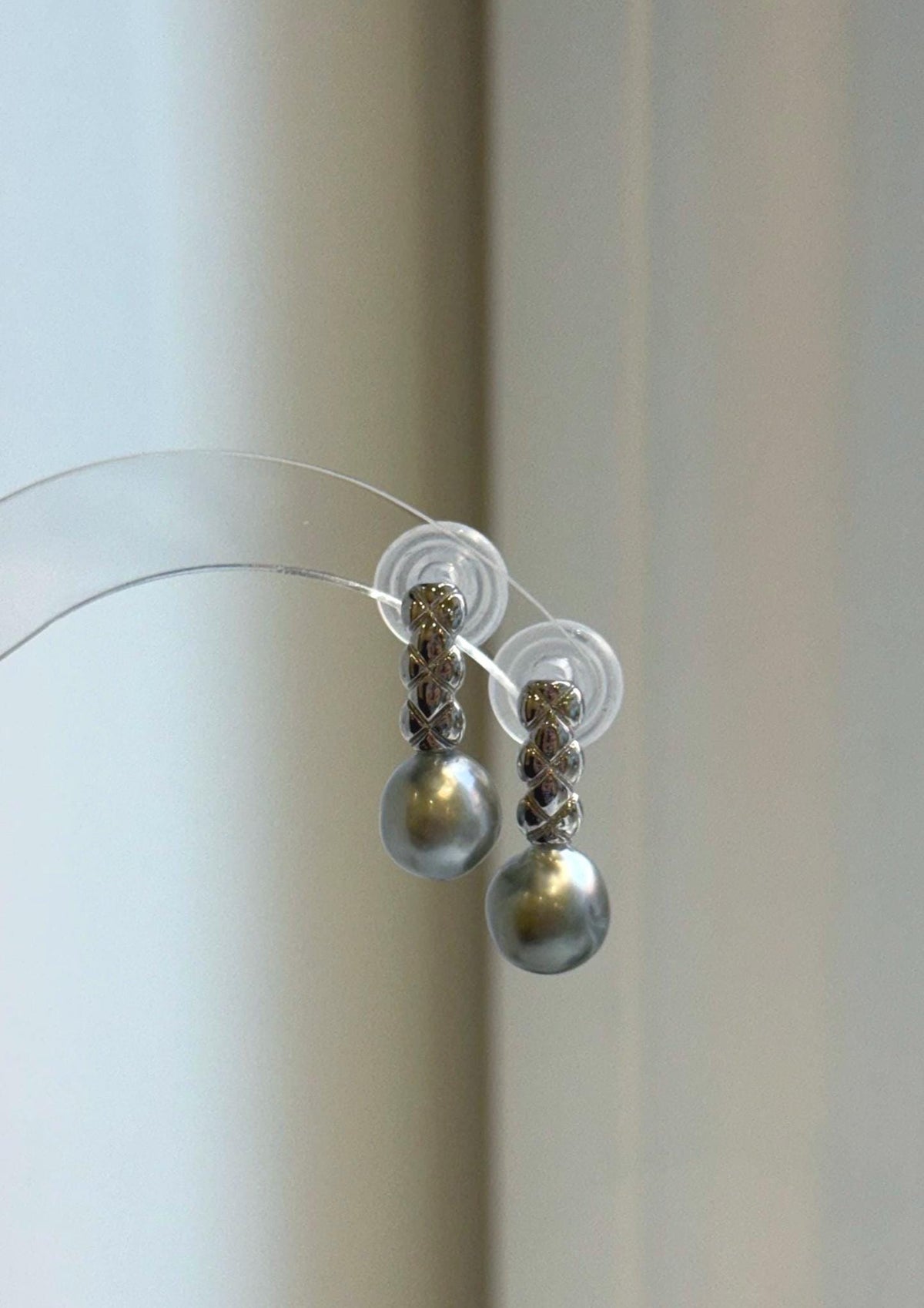 Elly’s 9mm gray pearl drop earrings with S925 sterling silver crisscross links, displayed on a clear stand.