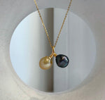 Two-pearl necklace with contrasting golden and dark green tones, displayed against a cream jewelry bust with an oval opening.