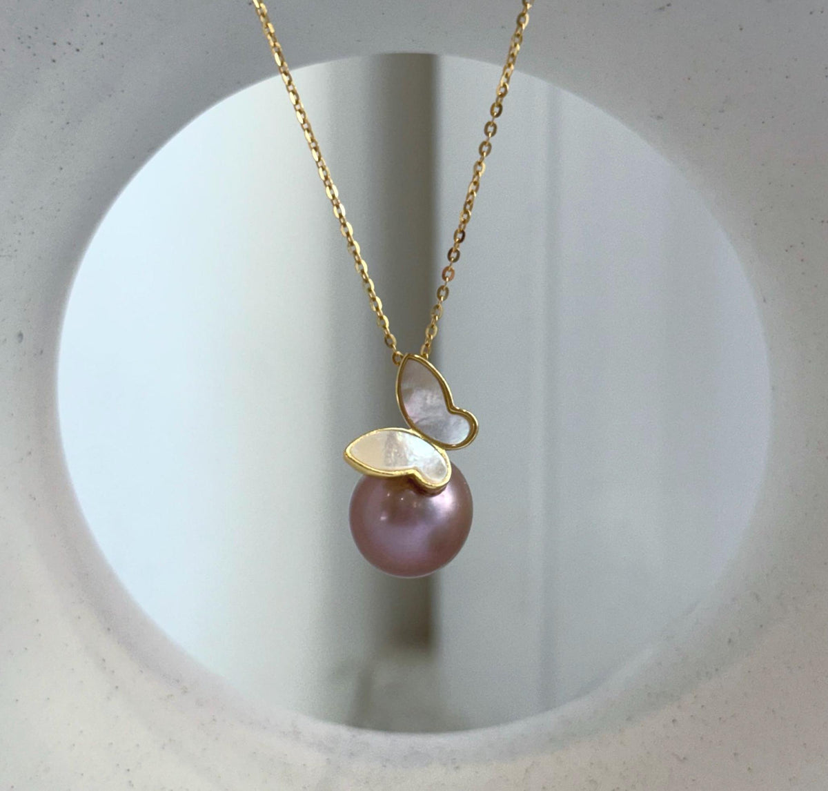 Rose lavender Edison pearl necklace with mirror luster and a silver butterfly design.