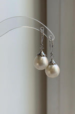 13.3mm white saltwater pearls featured in sterling silver drop earrings.