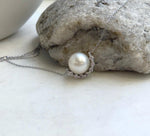 White saltwater pearl nestled in a sparkling crescent setting on a sterling silver pendant necklace.