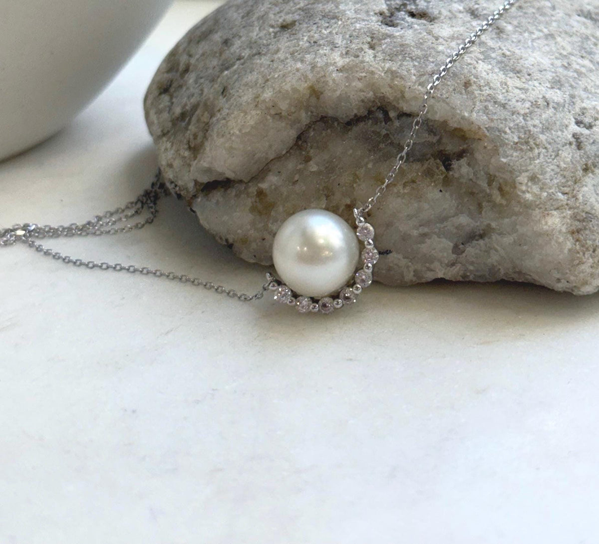 White saltwater pearl nestled in a sparkling crescent setting on a sterling silver pendant necklace.