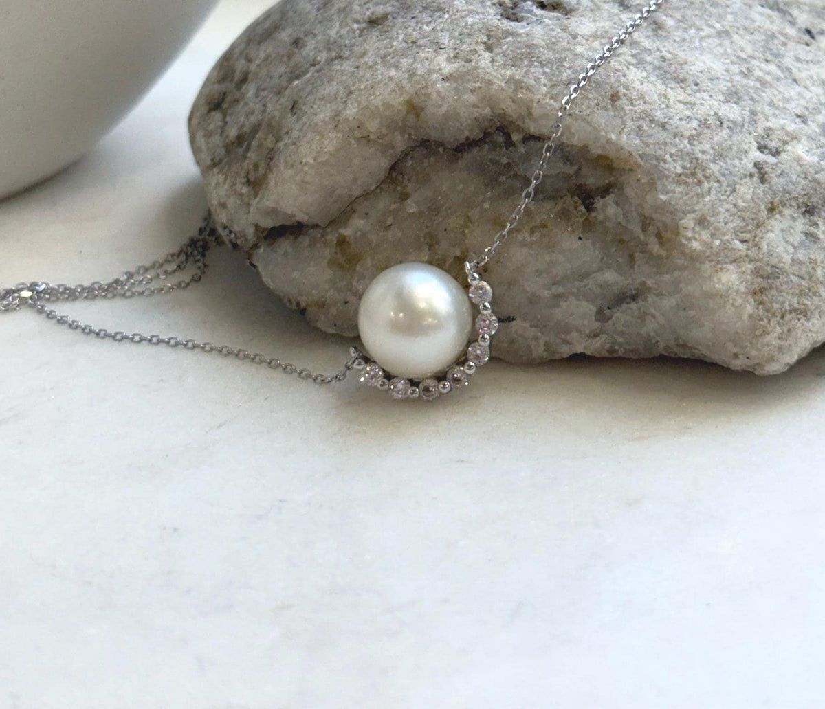White South Sea pearl pendant with a curved crescent design and sparkling accents.
