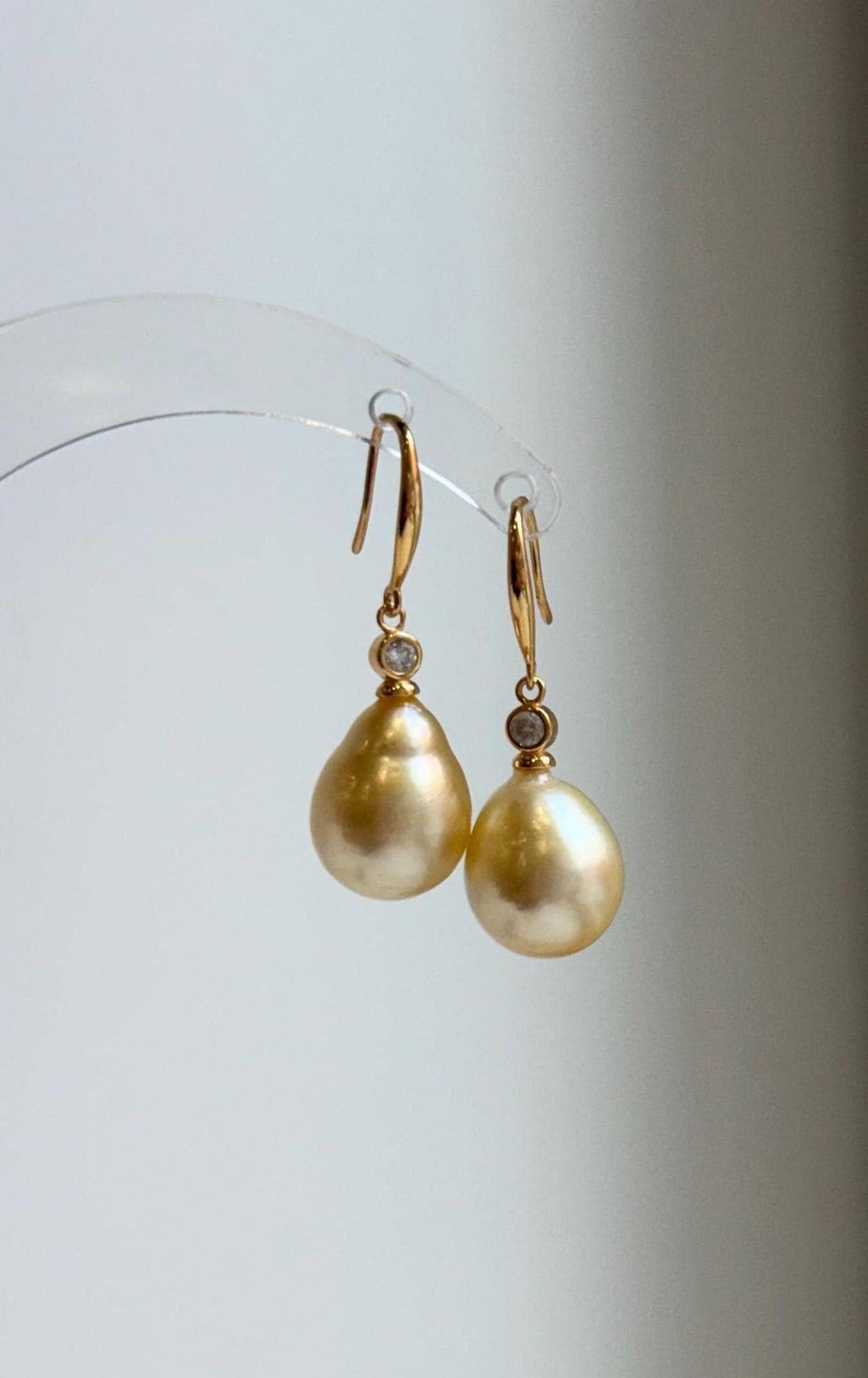 Golden saltwater pearl earrings with mirror luster and silver hooks.