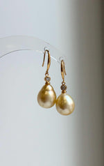 Golden saltwater pearl earrings with mirror luster and silver hooks.