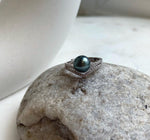 Peacock green Tahitian pearl above a V-shaped sterling silver setting.