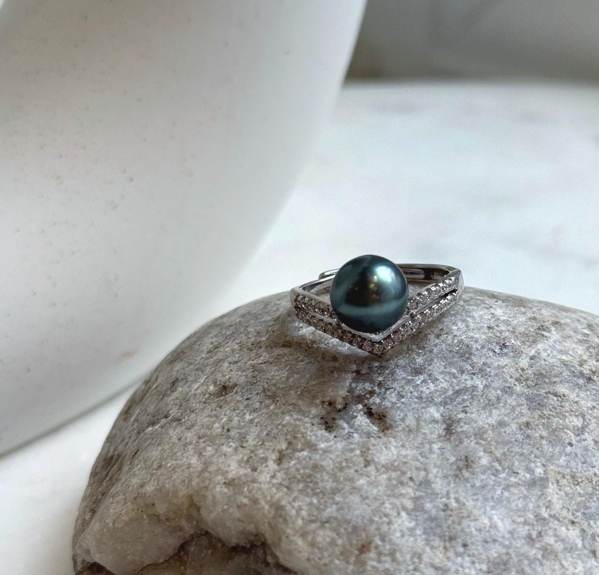 Dark peacock green saltwater pearl framed by a sparkling chevron band.